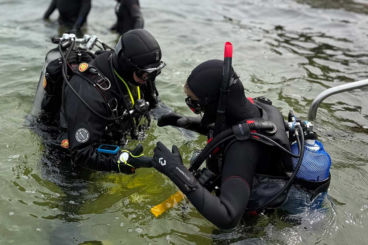 Instructeur en gast in het water tijdens een introductieduik bij Duikschool de Grevelingen